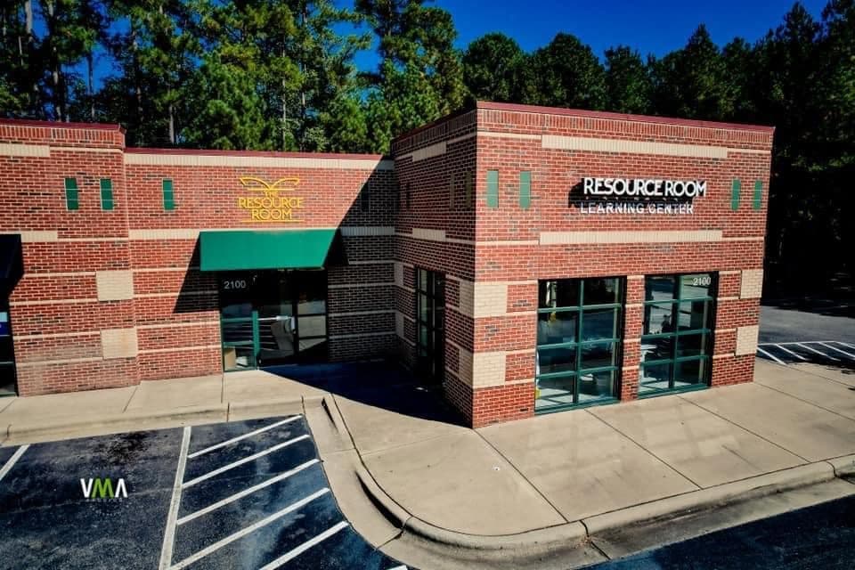 The Resource Room Learning Center building at 2100 Crossway Lane in Holly Springs — red brick with a green awning and the Resource Room sign above the entrance.
