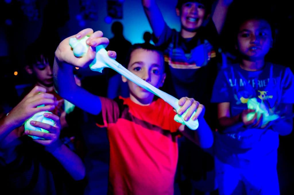 Campers stretching glow-in-the-dark slime during a hands-on STEAM camp activity.