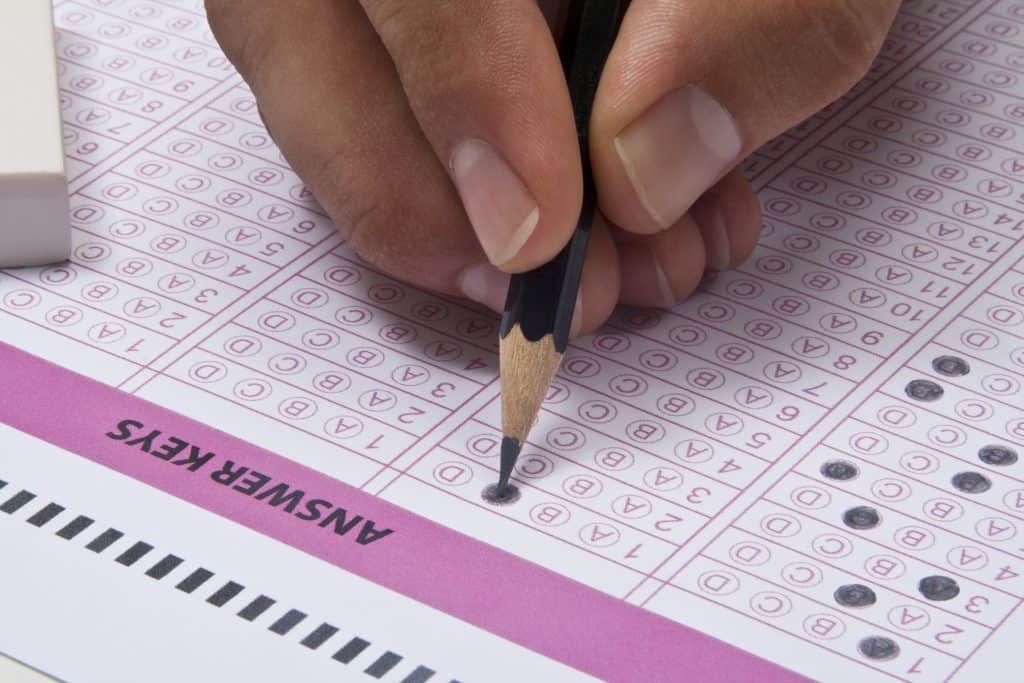 A student filling in bubbles on a standardized test answer sheet with a pencil.